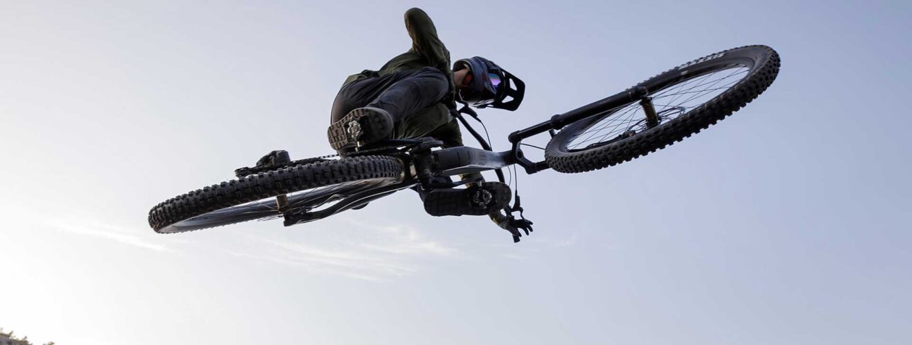 Cyclist jumps over an obstacle with a Cube 2026 bike in front of a waterfall.
