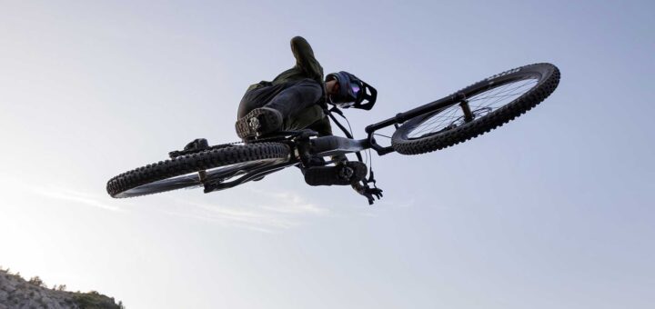 Cyclist jumps over an obstacle with a Cube 2026 bike in front of a waterfall.
