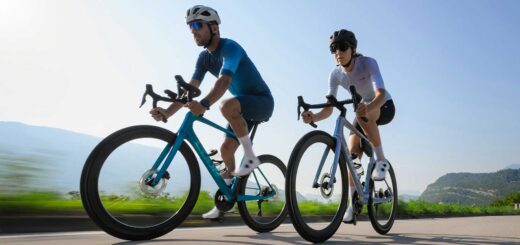 Two road cyclists (male and female) riding a 2026 Cube road bike in motion.