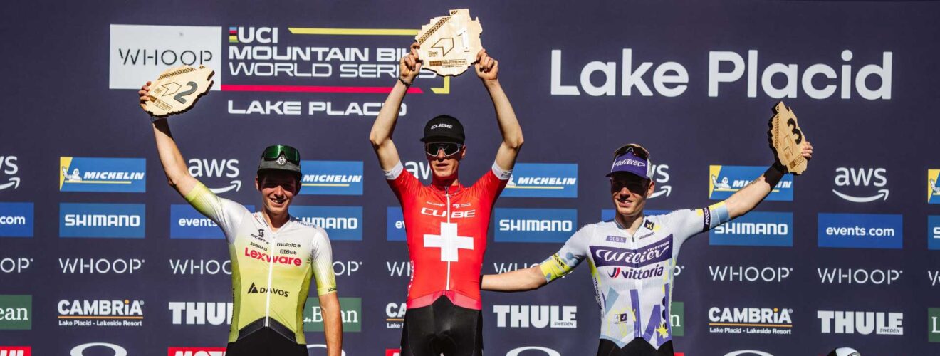 Finn Treudler celebrates on the podium, proudly raising the trophy for his U23 triumph in Lake Placid.